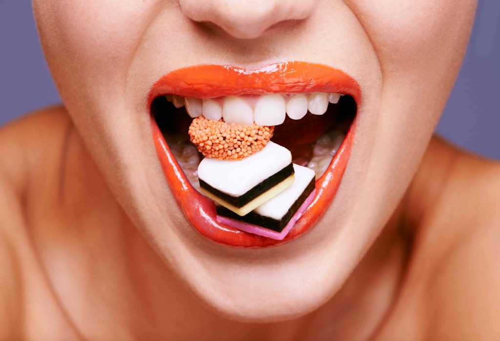 Close-up of a woman biting candy, highlighting how sugary treats can harm teeth