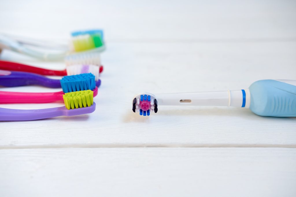 Electric toothbrush next to a manual toothbrush on bathroom counter